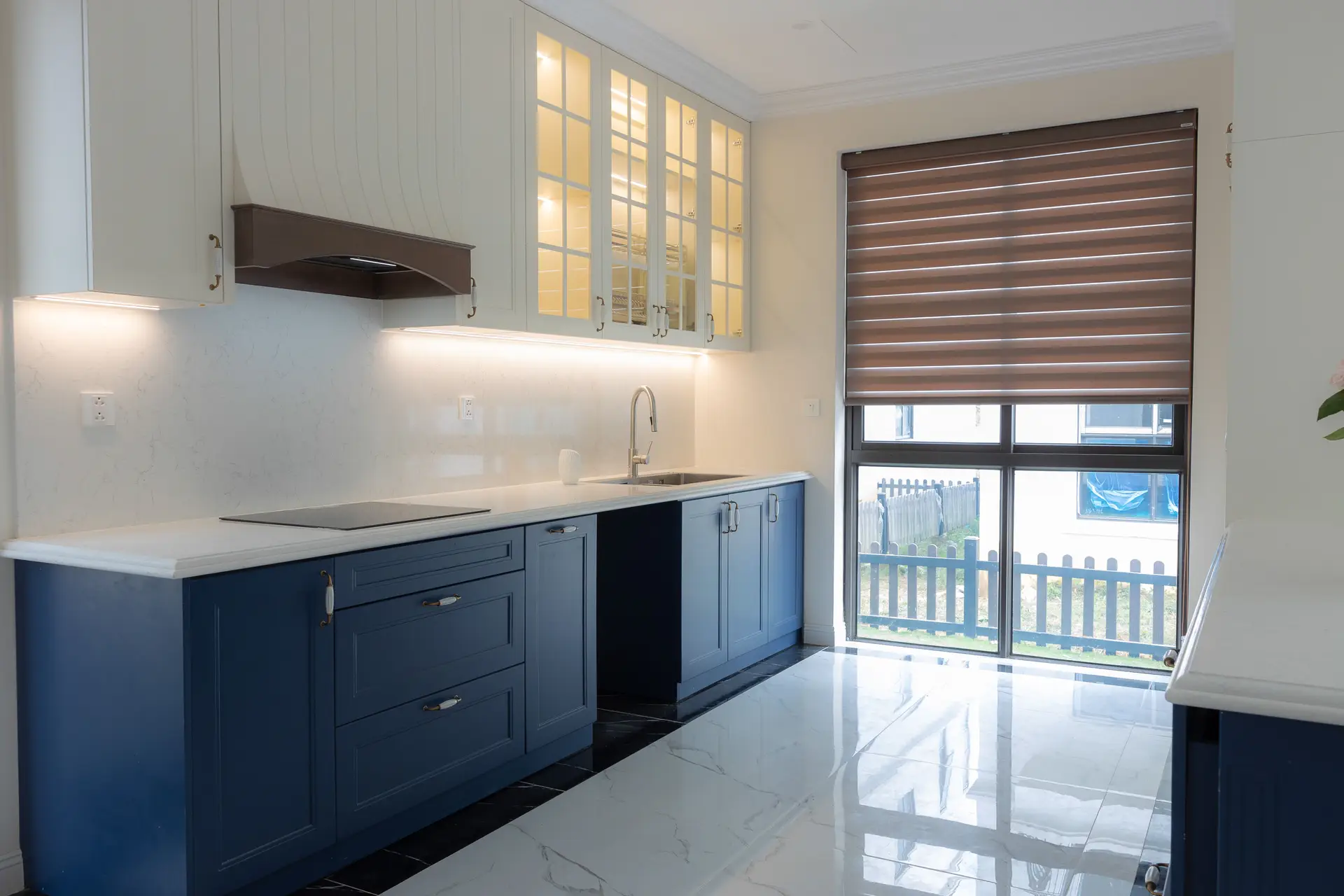 Kitchen with blue base cabinets, white countertops and a window blind