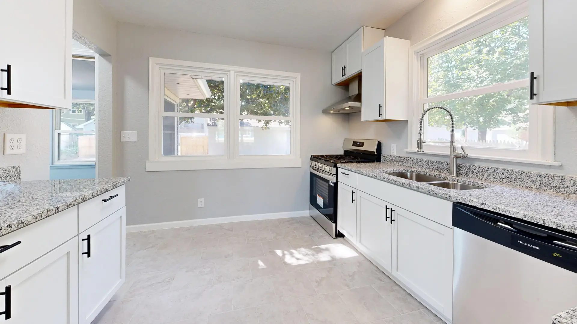 White kitchen with granite countertops and windows above the sink