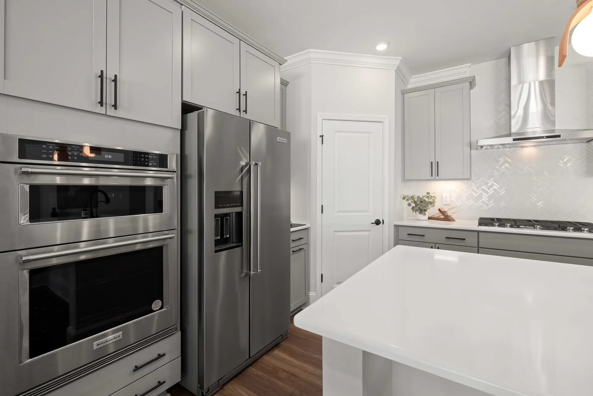 White kitchen with a large island, stainless steel refrigerator and double wall oven