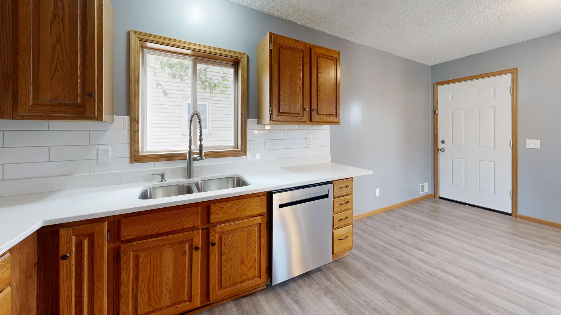 Kitchen with wood cabinets, white tile backsplash and a window above the sink